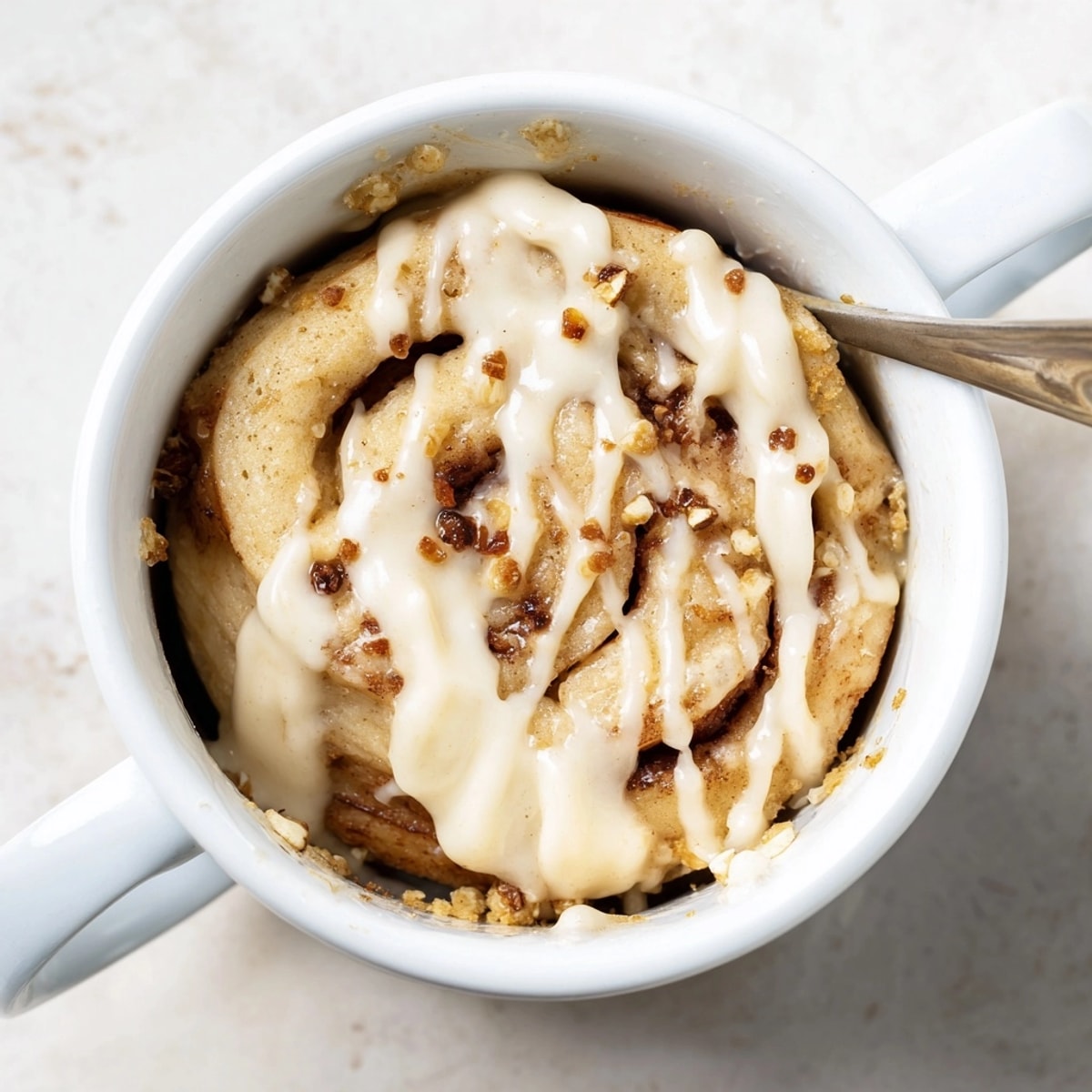 Close-up of delicious, fluffy Protein Cinnamon Roll Mug Cake, swirled with cinnamon and topped.