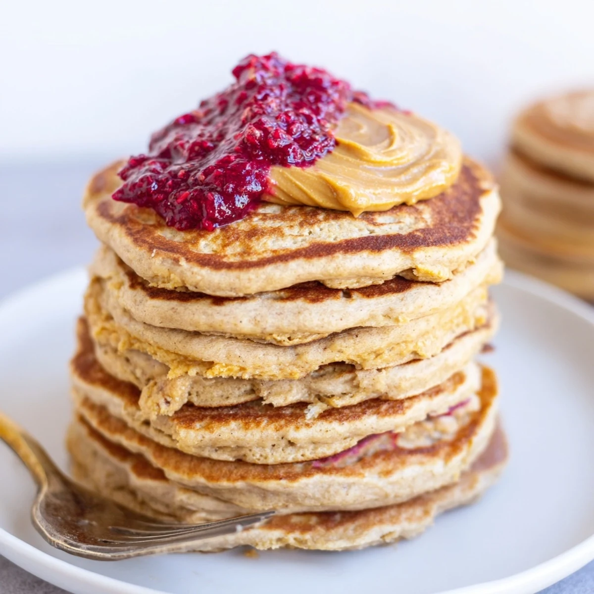 Fluffy Fitness Protein Pancakes stacked with banana and topped with nut butter.  