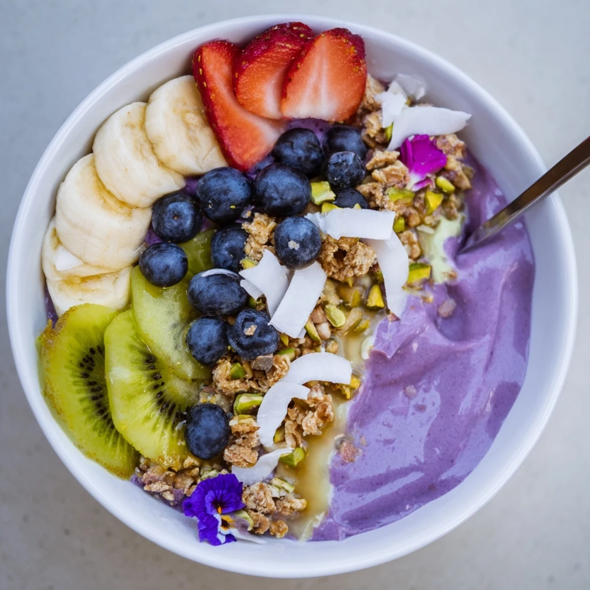 Colorful breakfast smoothie bowls adorned with kiwi, granola, and crunchy pistachios.  