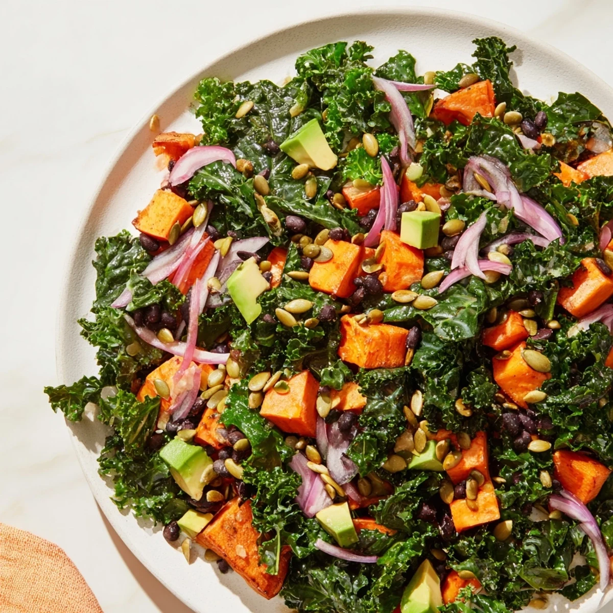 Vibrant massaged kale salad with sweet potato, black beans, and lime dressing: a delicious and healthy lunch.