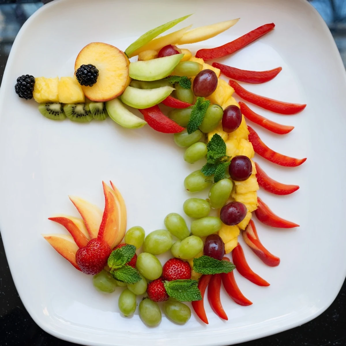 A healthy and whimsical Dragon-Shaped Fruit Tray with grapes, berries, and melon artfully displayed.