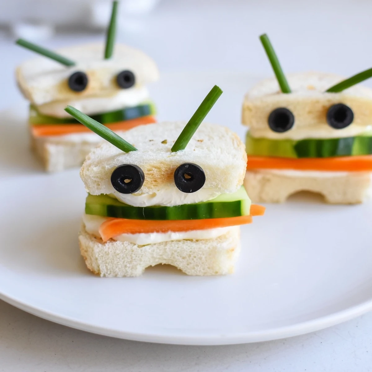 Playful bee sandwich cutouts featuring black olive stripes sit next to ripe, juicy strawberries.