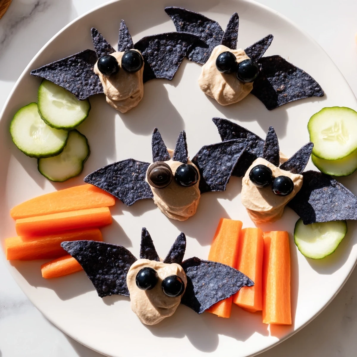 Enjoy this vibrant Spooky Bat Bean Dip Platter, a Halloween dish with black olives and crunchy dippers.