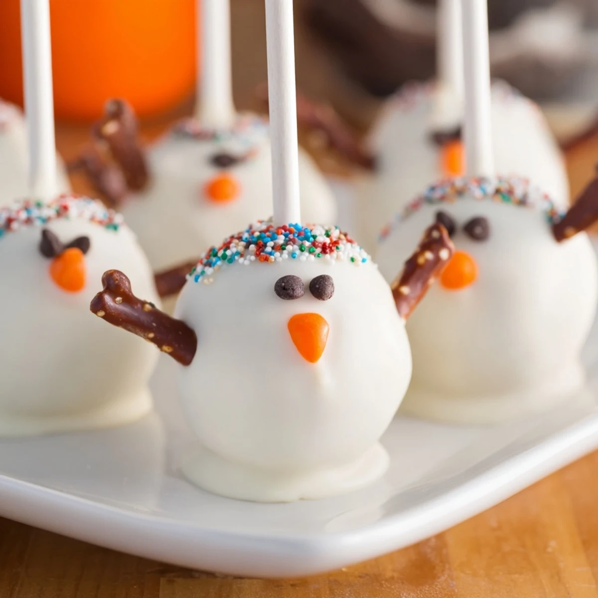 Oreo Snowman Cake Pops, coated in white chocolate, ready for a winter holiday treat, garnished with a pretzel arm.