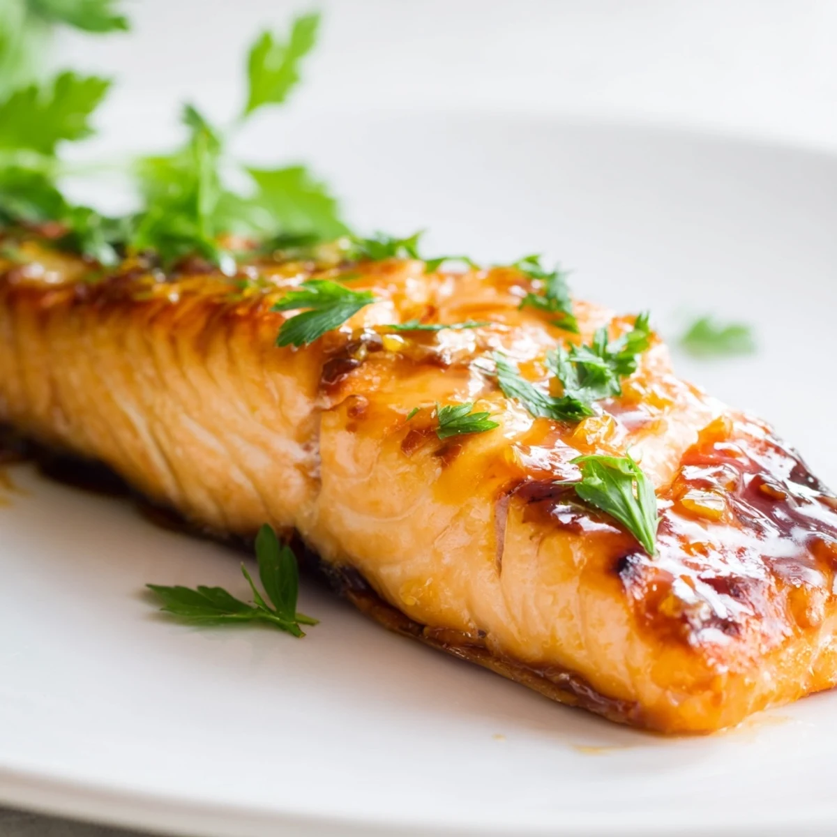 Golden-brown Honey Garlic Glazed Salmon fillets roasted to perfection on a baking sheet with fresh parsley garnish.