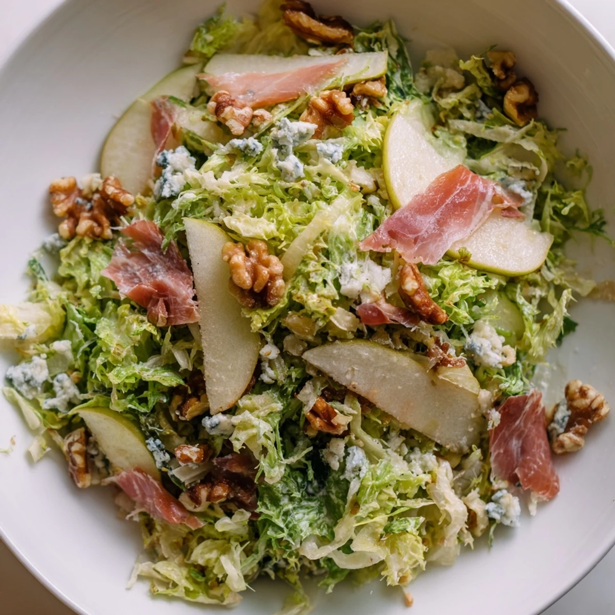 Glistening pear slices and crumbled blue cheese nestle among frisée leaves, topped with crispy prosciutto shards for this elegant salad.