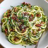 A vibrant image of Zucchini Noodle Carbonara, ready to serve with fresh parsley garnish and crunchy turkey bacon.