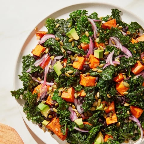 Vibrant massaged kale salad with sweet potato, black beans, and lime dressing: a delicious and healthy lunch.