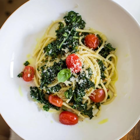 Steaming one-pot spaghetti with kale & tomatoes, garnished fresh, inviting Italian comfort food for dinner.