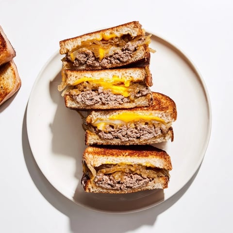 Golden-brown patty melt skillet with oozing Swiss cheese, onions, and flavorful beef, ready to eat.