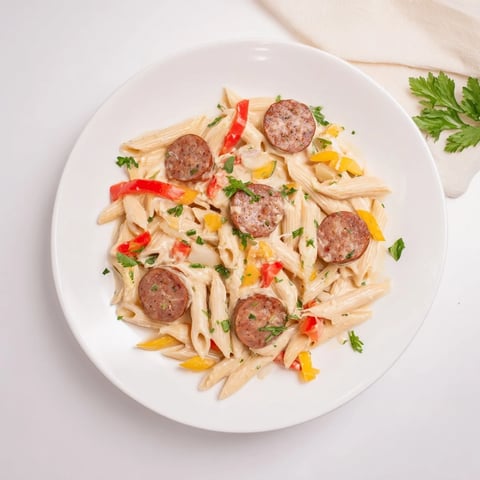 Savory Smoked Sausage Cajun Alfredo with penne, ready to eat with vibrant red peppers and parsley.