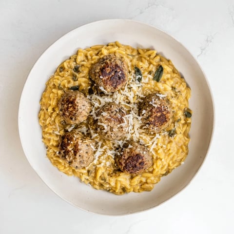 Tender sage turkey meatballs nestled in vibrant pumpkin orzo, a complete and flavorful meal.