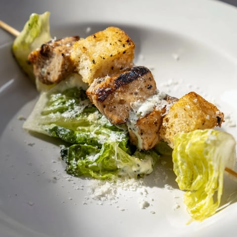 Grilled Chicken Caesar Salad Skewers served with a drizzle of creamy dressing and Parmesan, ready to eat.