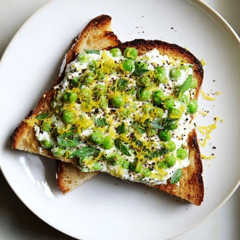 Freshly spread Pea & Mint Ricotta Toast on toasted sourdough, topped with bright lemon zest for a vibrant, creamy bite.  