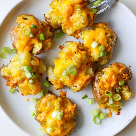 Crispy smashed green onion potato bombs topped with melted cheddar and fresh herbs.  