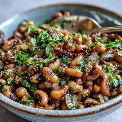 Seasoned Frozen Black-Eyed Peas simmered in a savory broth with diced tomatoes and aromatic herbs in a rustic bowl.