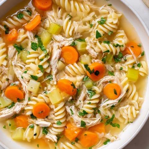 A close-up view of creamy Crockpot Chicken Noodle Soup, showcasing the fresh vegetables and broth.