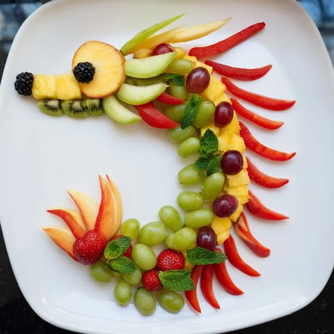 A healthy and whimsical Dragon-Shaped Fruit Tray with grapes, berries, and melon artfully displayed.