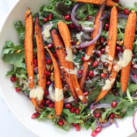 A close-up of a colorful Roasted Carrot Salad, boasting a creamy tahini-lemon dressing.