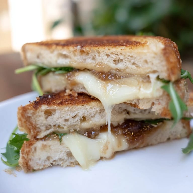 Perfectly browned Fig, Brie & Arugula Grilled Cheese, served with a side of peppery arugula.