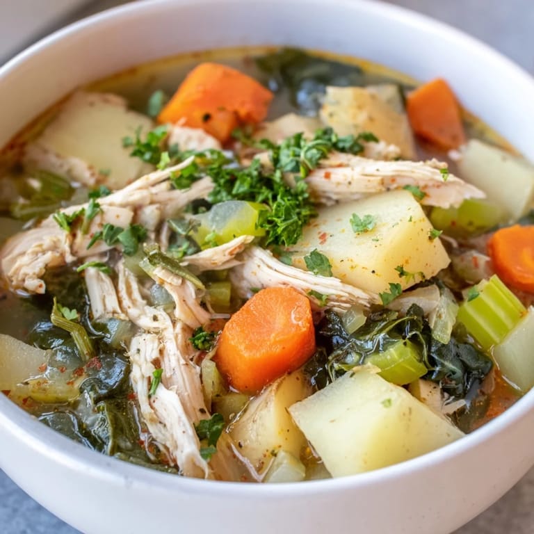 Close-up of Collard Greens, Chicken and Vegetable Soup showing vibrant green leaves, carrots, and celery simmering in a rich, flavorful broth.