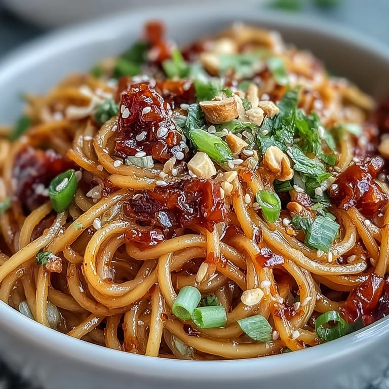 Savory chili crisp noodles topped with crunchy peanuts and scallions, delivering a spicy, satisfying Asian fusion main dish.