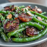 Vibrant green beans roasted with golden garlic slices, finished with a bright lemon zest for a savory side dish.