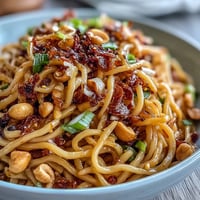 Spicy chili crisp noodles with chewy wheat noodles, crunchy garlic, and fresh scallions in a savory sauce.